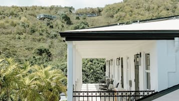 Un edificio blanco con balcón que da a una piscina y palmeras.
