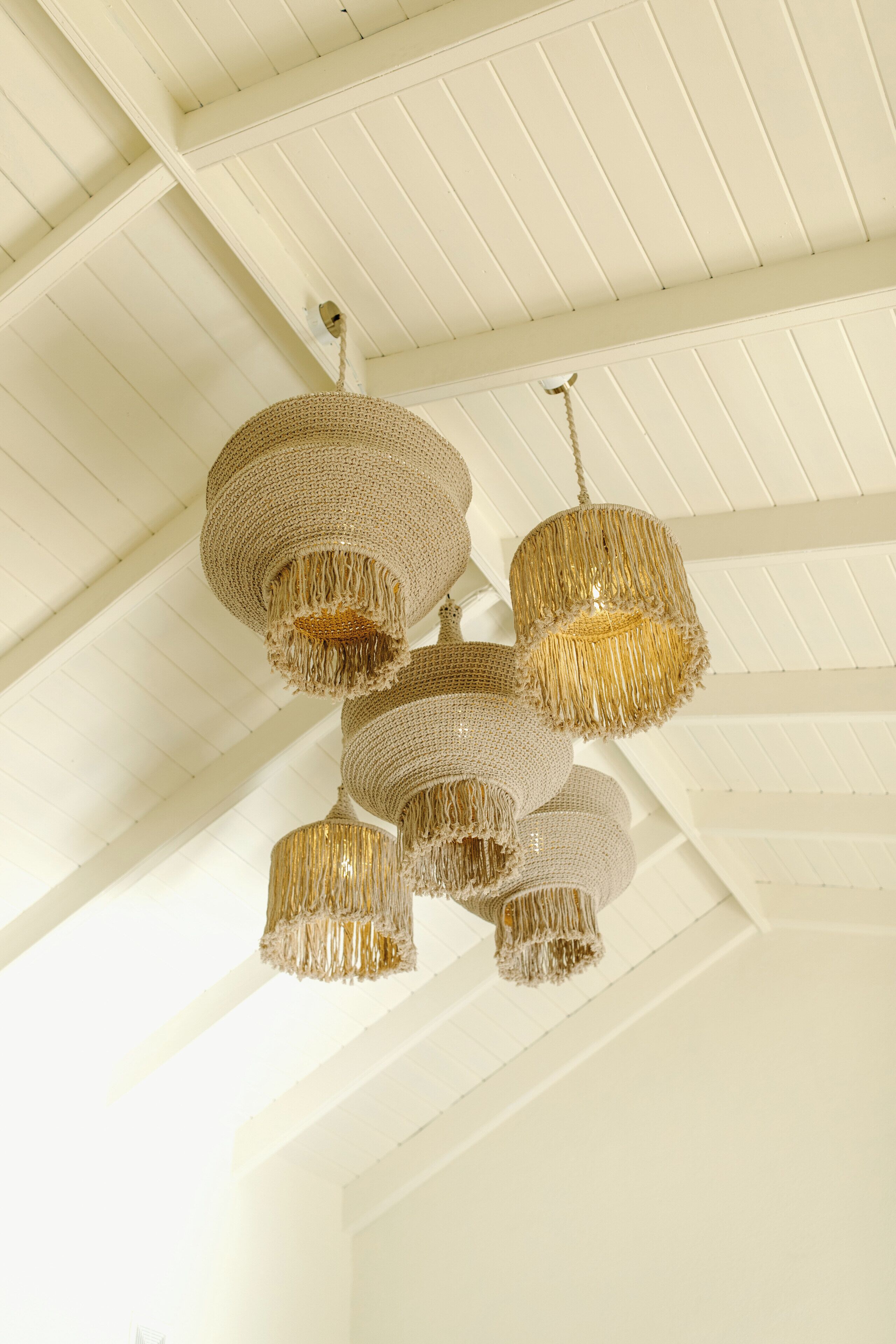 A ceiling with a white wooden structure and multiple hanging chandeliers.