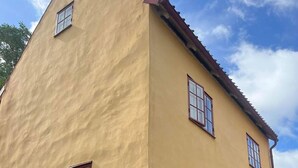 A corner of a building with a yellow facade and a red roof. - Awesome home in Visby innerstad (Visby innerstad)