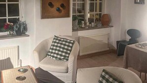 A living room with a white armchair, a sofa, a small table, and a radiator. - Awesome home in Visby innerstad (Visby innerstad)