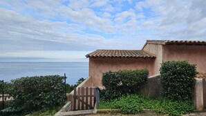 A coastal building with a tiled roof, surrounded by greenery and a wooden fence. - MINI-VILLA - LEA TARCO - SEA VIEW - AIR CONDITIONING (TARCO CONCA)
