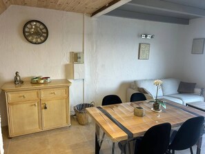 A dining area with a wooden table, chairs, a cabinet, a Buddha statue, and a clock on the wall.