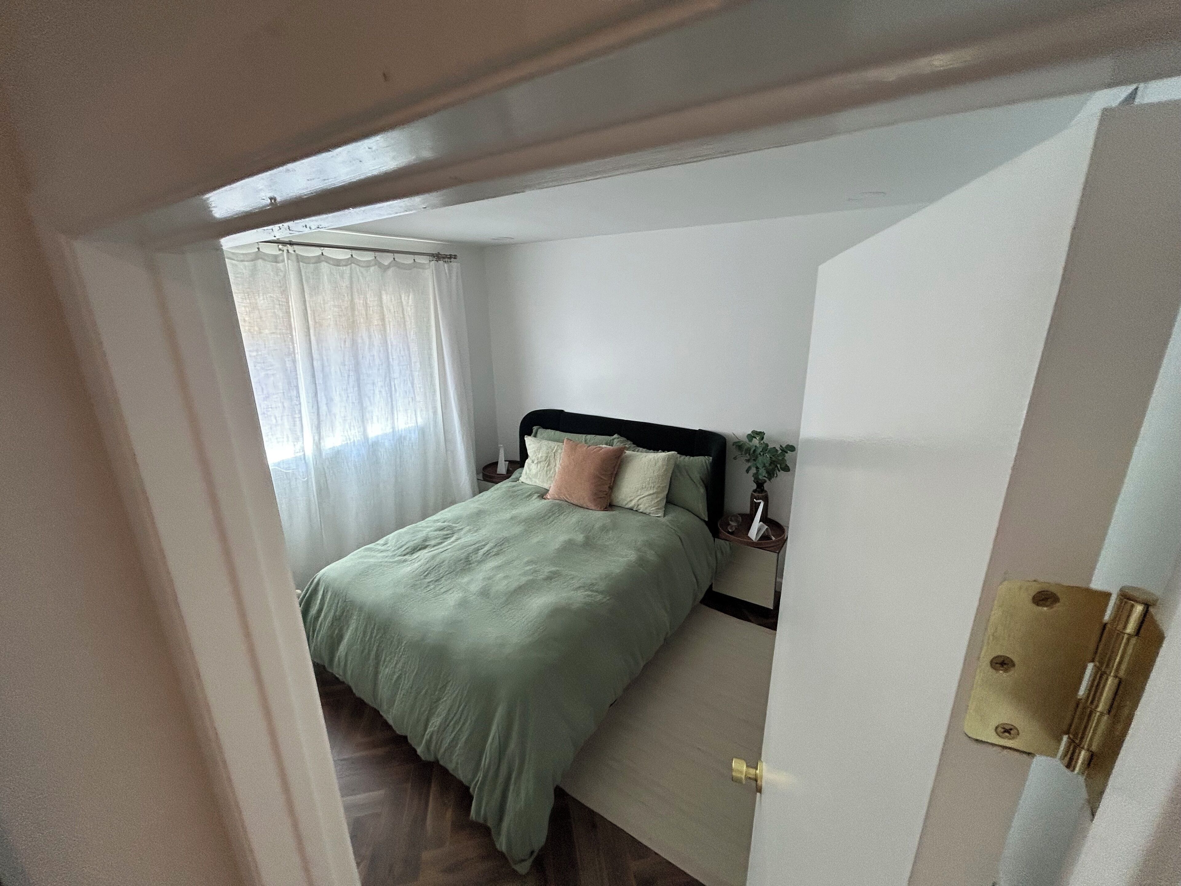 Ein Schlafzimmer mit einem Bett, einem Nachttisch und einem Fenster mit Vorhängen.