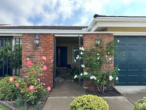 A residential house with a brick exterior, a garage door, and a front entrance. - Mid Century Mod 3 bed stunner in Huntington Beach w/ A/C & Fibre 1 mi to beach (Huntington Beach)