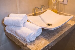 A bathroom with a marble sink, a towel rack with folded towels, and a soap dispenser. - Ambar - Sea front charming house, 1.5kms from old town,, swimming pool, BBQ. WiFi (Jabaquara Paraty)