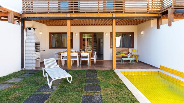 En moderne udendørs terrasse med spiseplads, pool og grill.
