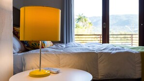 Et hotelværelse med en seng, et natbord med lampe, og udsigt til det fri.