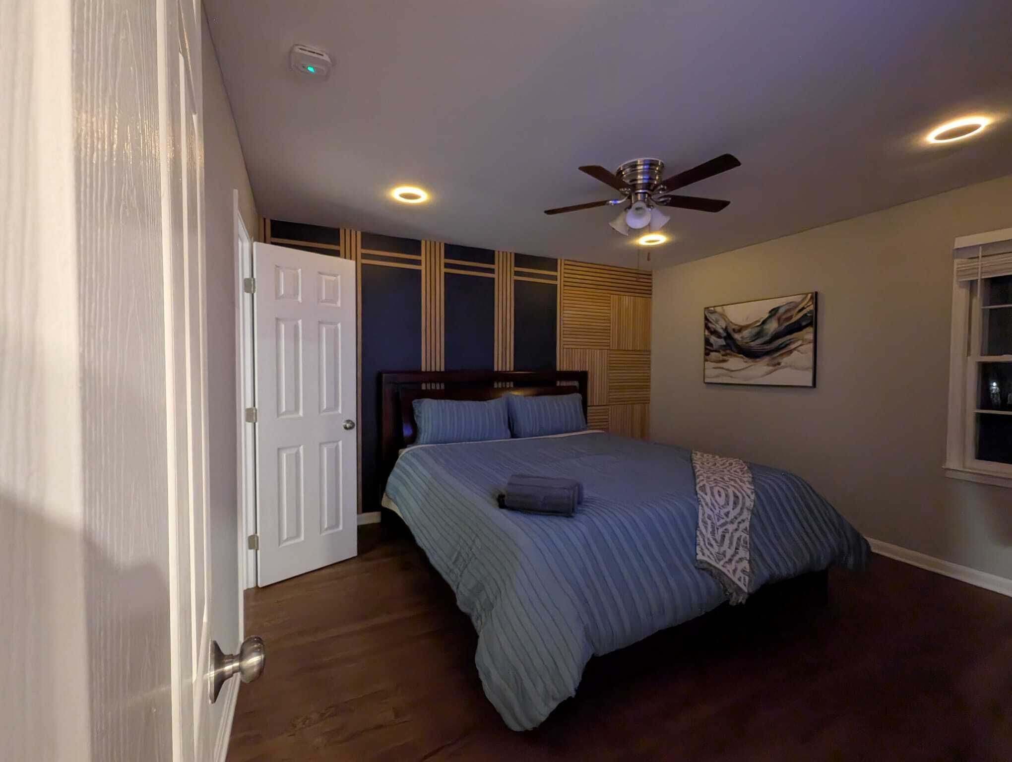 Une chambre à coucher avec un lit, un ventilateur de plafond, une porte et une fenêtre.
