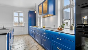 Une cuisine moderne avec des armoires bleues, une grande fenêtre et une vue sur l’extérieur.