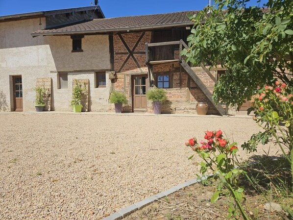 Un bâtiment doté d’une façade en pierre, de poutres en bois et d’une allée gravillonnée.