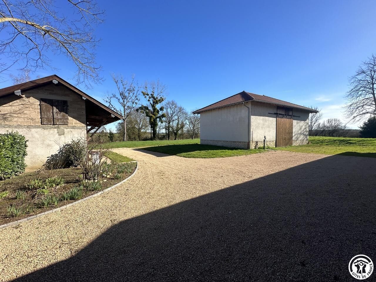A gravel driveway leading to a building with a sloped roof and a small porch.