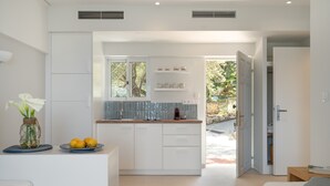 Una cocina moderna con armarios blancos, horno empotrado y ventana con vista a la vegetación.