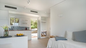 Habitación de hotel moderna con una cama blanca, una mesita de noche pequeña, un ventanal grande y vistas al exterior.