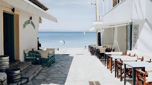 Una calle estrecha con mesas al aire libre y vista al mar.