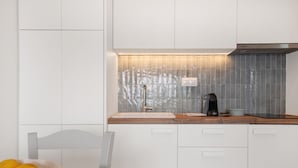 Une cuisine moderne avec des armoires blanches, un plan de travail en bois et un revêtement mural en carreaux.