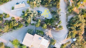 Vista aérea de una propiedad con piscina, un edificio grande y follaje circundante.