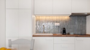 A modern kitchen with white cabinets, a wooden countertop, and a tiled backsplash.