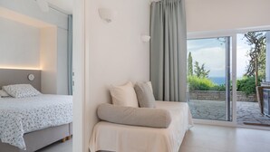 A bedroom with a bed, a sofa, a window, and a view of the outdoors.