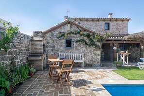 A stone building with a pool, wooden furniture, and potted plants. - Holiday Home 'Laura' with Shared Pool, Wi-Fi and Air Conditioning (Conil de la Frontera)