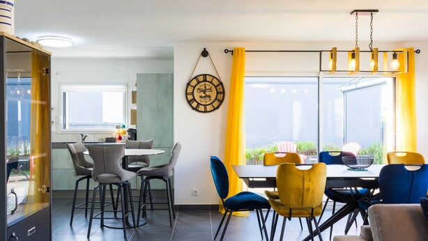 Una cocina moderna con comedor, un reloj grande y vistas por la ventana.