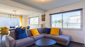 Una sala de estar moderna con un sofá modular, una mesa de centro redonda y un comedor con sillas y una mesa.