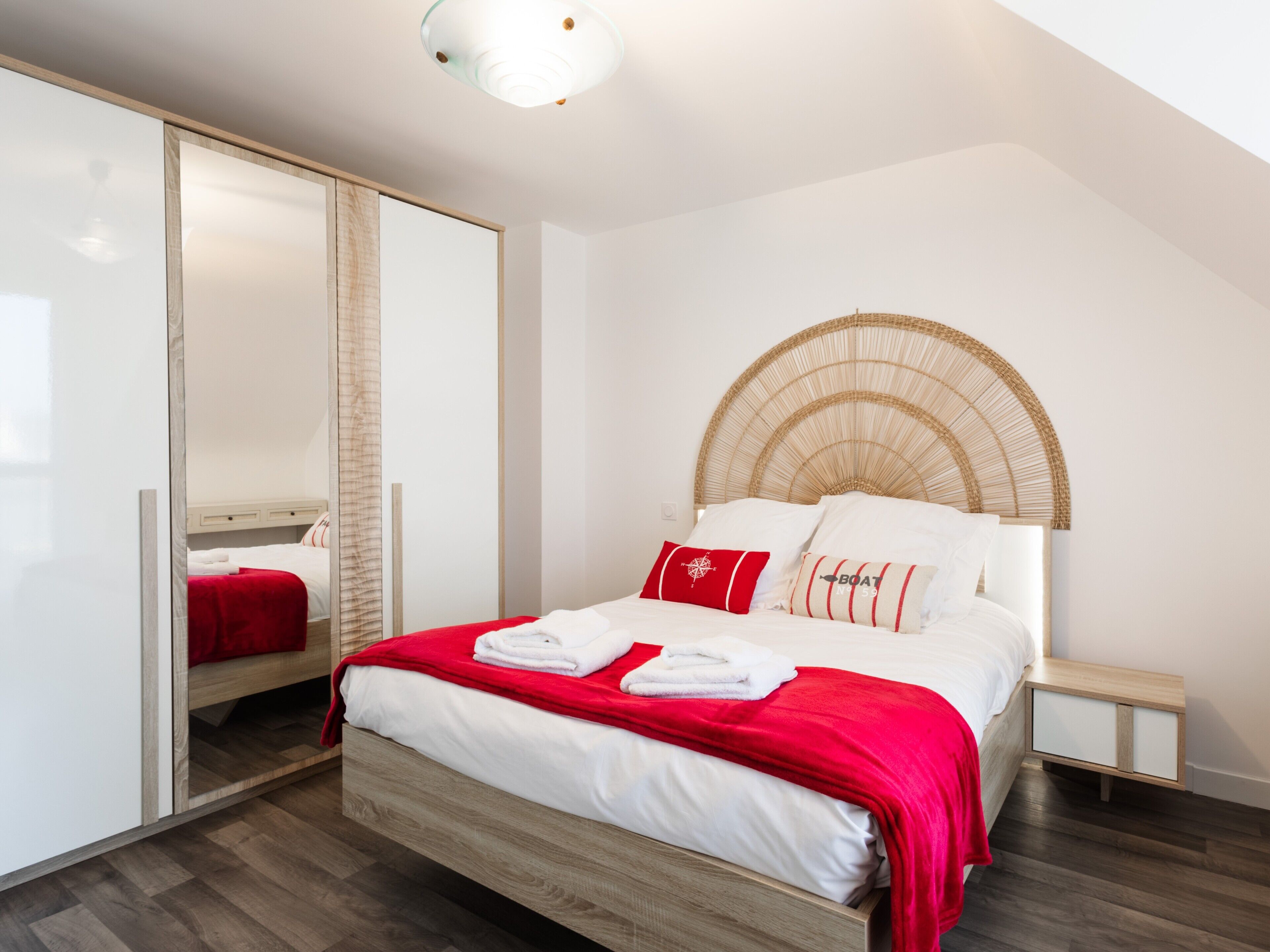 Une chambre moderne avec un lit, un miroir, une table de chevet et une armoire.