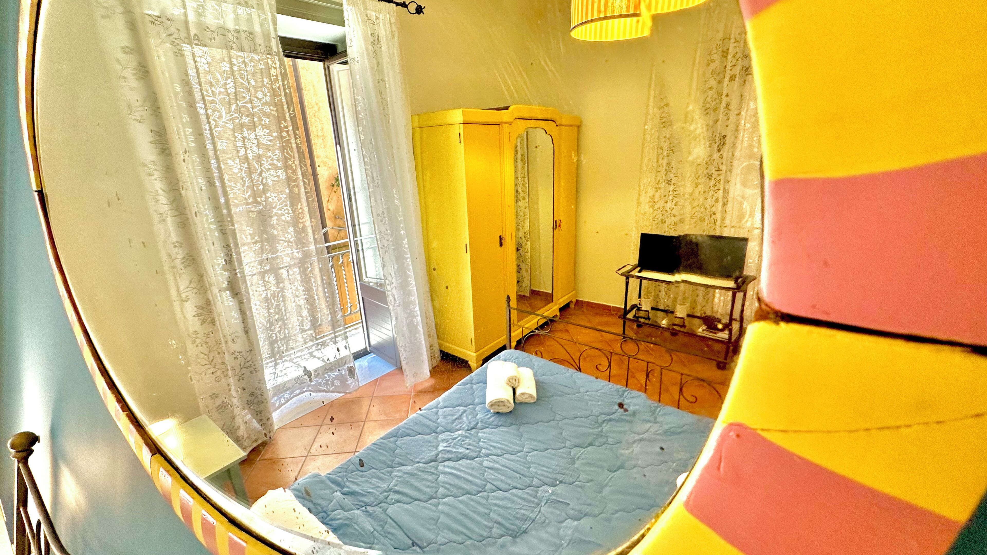 A room with a bed, a wardrobe, a bench, and a mirror.