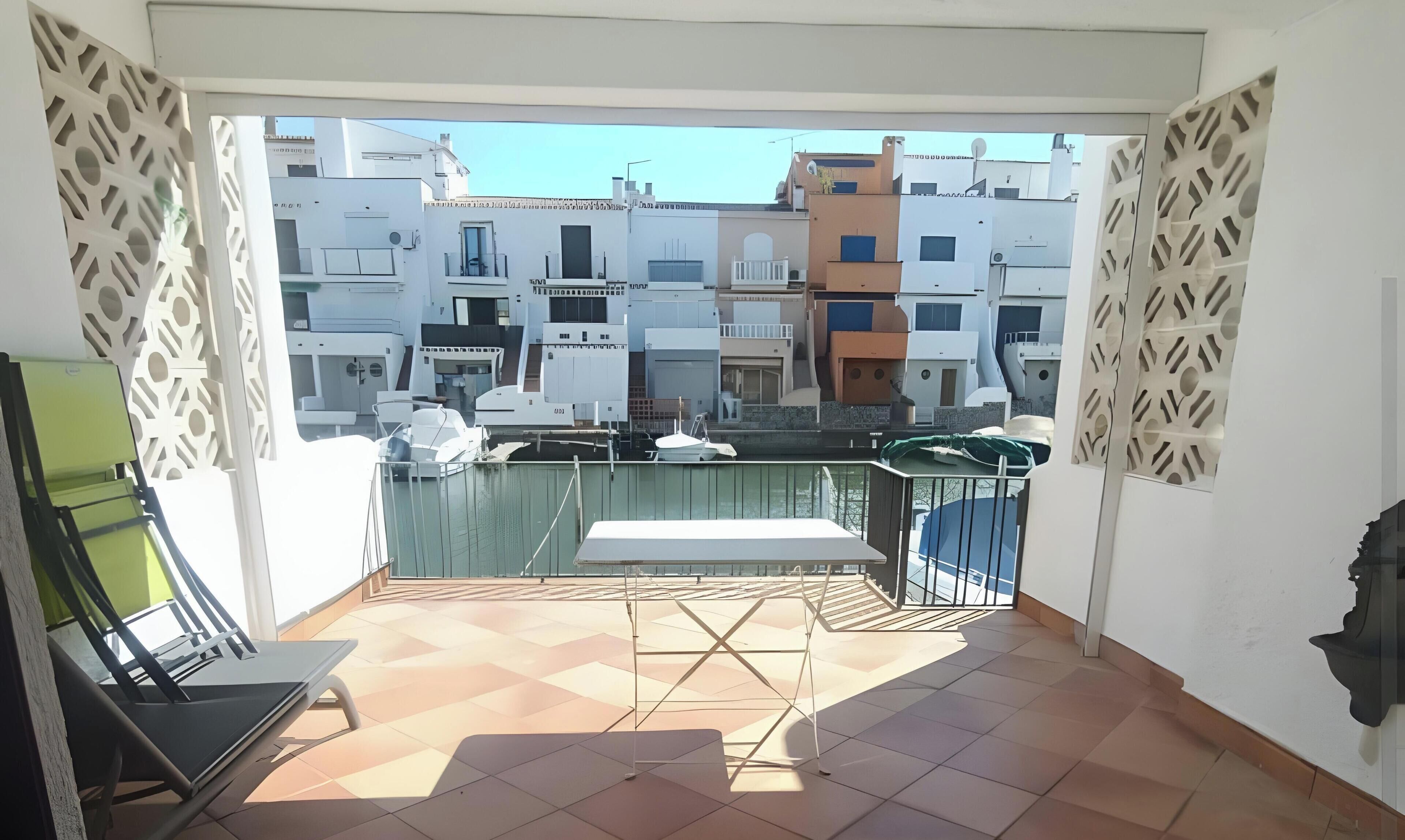 Een balkon met uitzicht op gebouwen, een boot en een stoel.