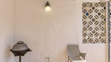 A room with a grill, a chair, a wall-mounted light fixture, and a decorative panel.
