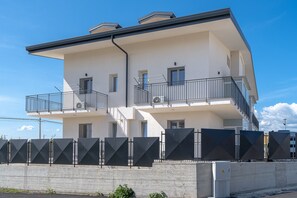 A multi-story building with balconies, a concrete barrier, and a clear sky.