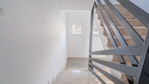 A staircase with a metal railing, a small window, and a plain white wall. - Room 'Leverblu  6' with Shared Terrace, Wi-Fi and Air Conditioning (Avola)