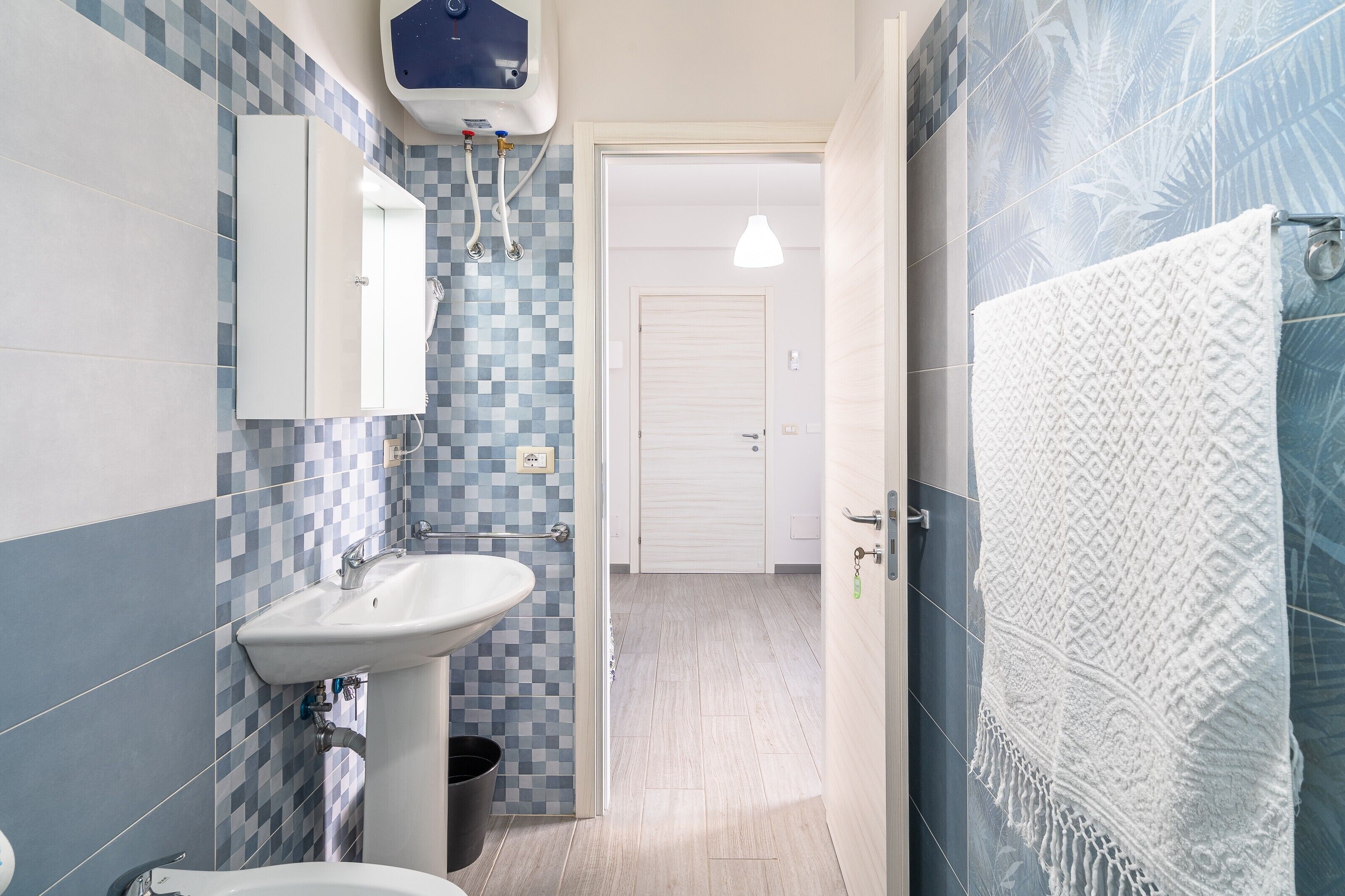 Une salle de bain équipée d’un lavabo, d’un miroir, d’un porte-serviettes et d’un espace douche.