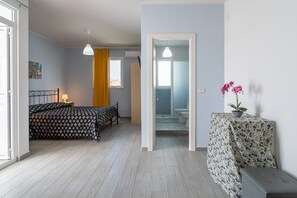 A bedroom with a bed, bedside table, and a view into the bathroom.