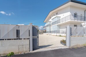 A gated entrance to a modern building with a balcony on the second floor.
