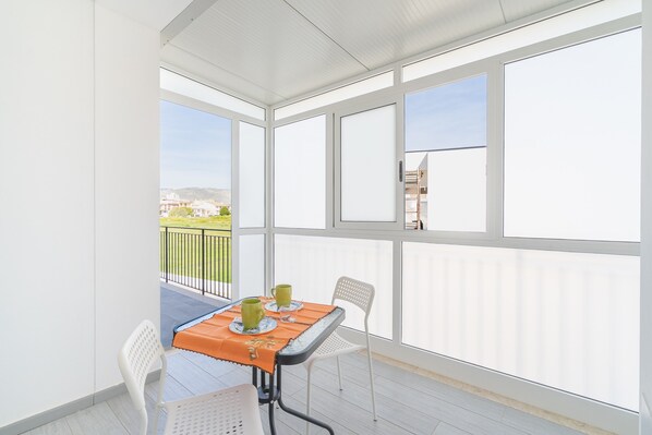 A balcony with a table, chairs, and a view of the city.