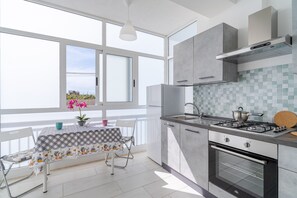 Eine moderne Küche mit einem großen Fenster, einem Esstisch mit Stühlen, einer Gasherd und einem eingebauten Backofen.