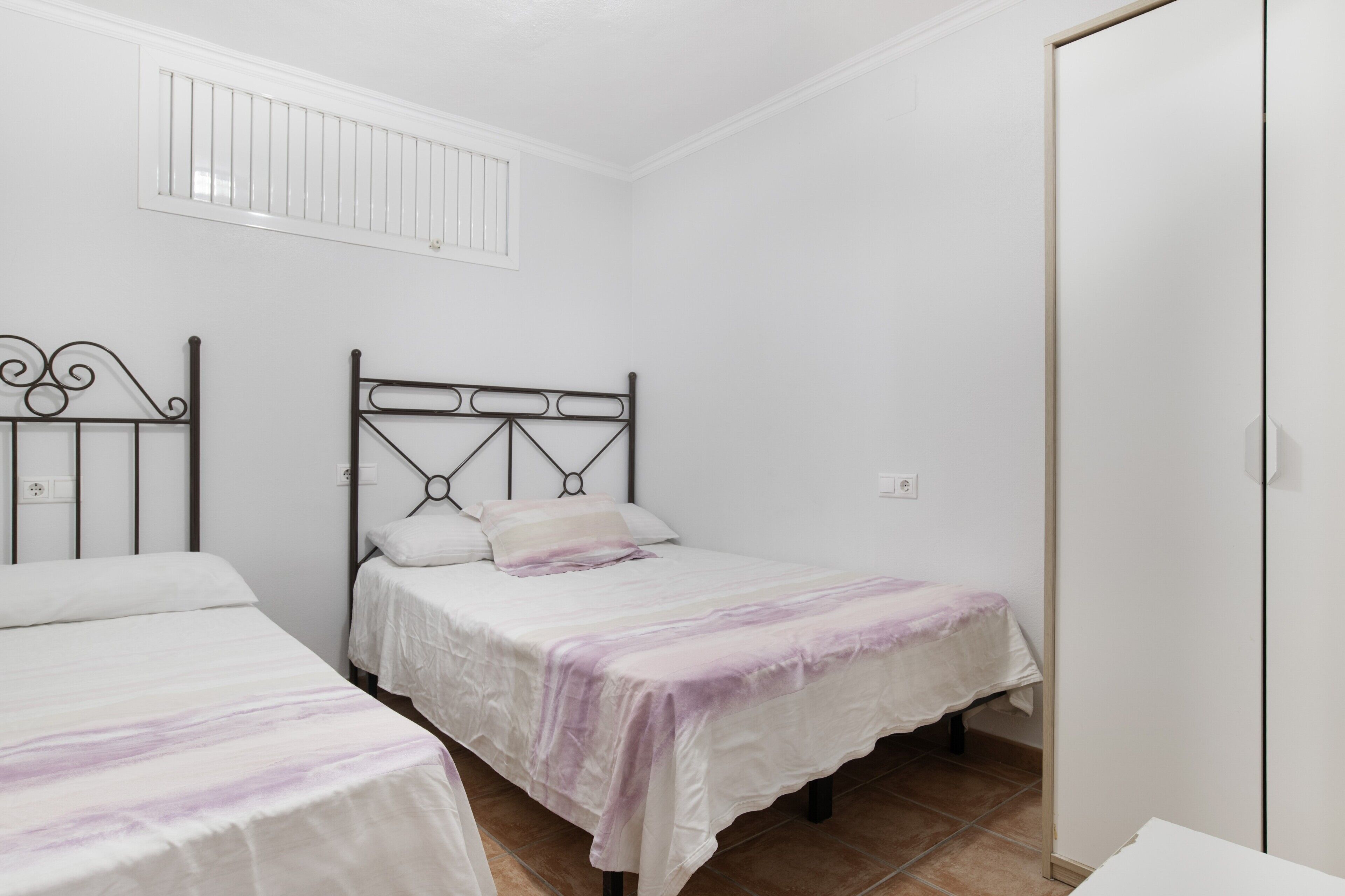 Un dormitorio con dos camas, techo blanco y puerta blanca.