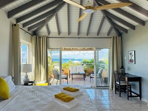 Una habitación de hotel con una cama, un escritorio, una silla y vista al océano.