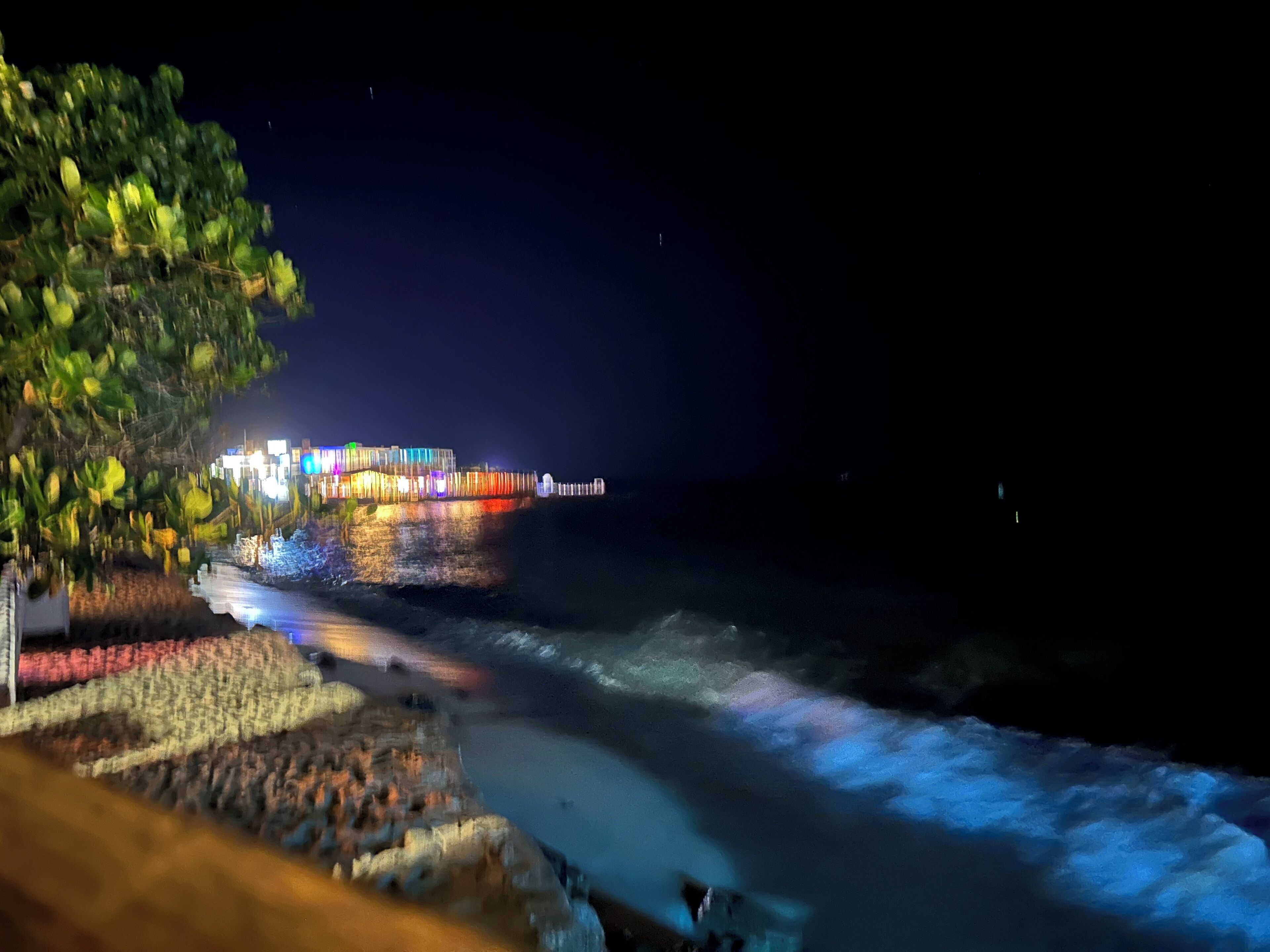 Ein nächtliches Küstengewand mit einem hell beleuchteten Gebäude und einer Pier, die sich ins Wasser erstreckt.