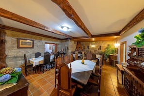 A dining area with stone walls, wooden beams, and a tiled floor.
