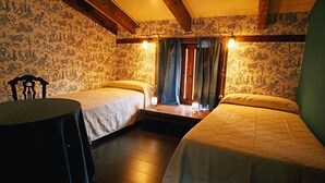 Une chambre avec deux lits, une table et une fenêtre avec des rideaux.