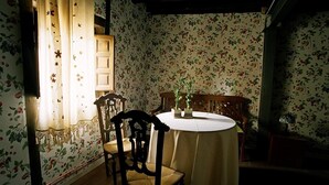 Un coin repas avec une table ronde, des chaises et un papier peint à motifs floraux.