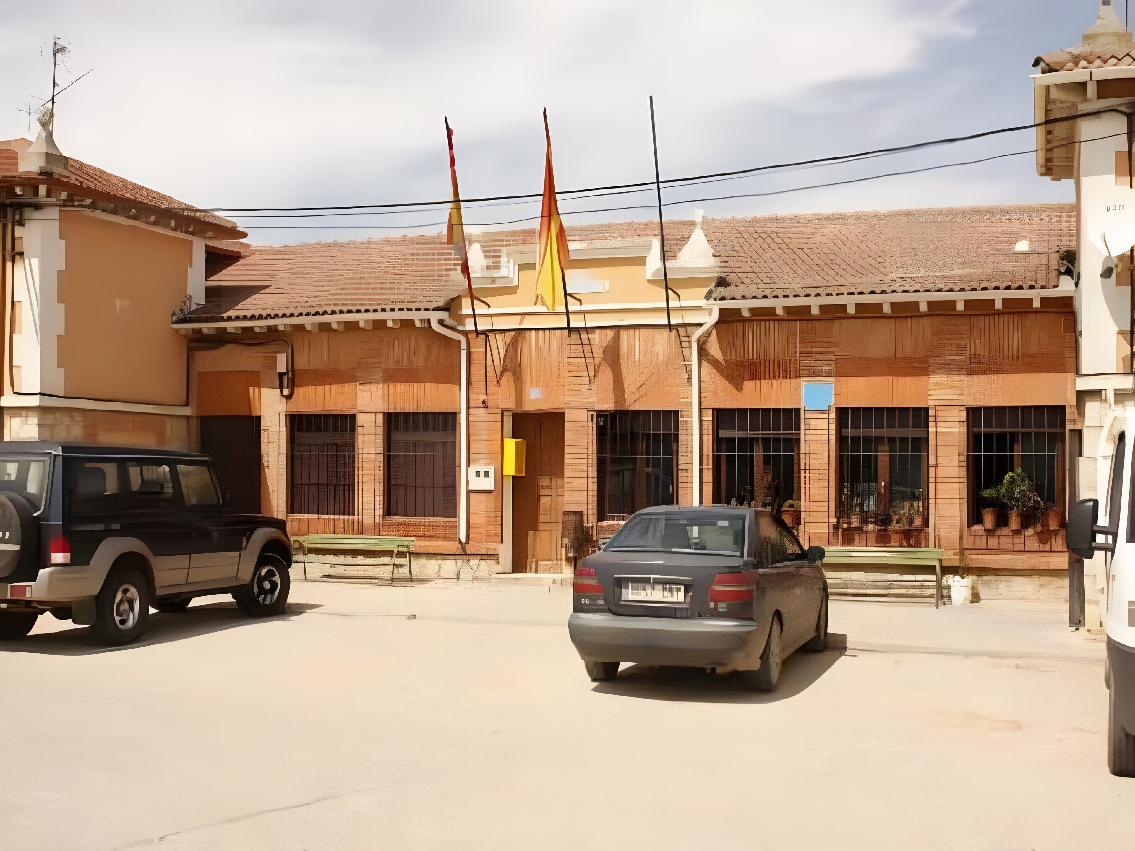 A building with a tiled roof, a parked car, and a parked SUV.