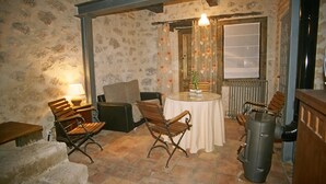Una habitación acogedora con pared de piedra, una mesa redonda con sillas, un radiador y una lámpara.