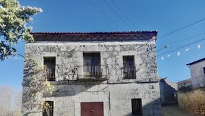 Un edificio de dos pisos con puerta roja, ventanas con rejas y un balcón.
