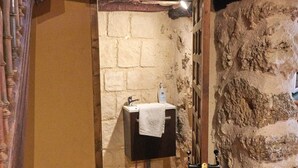 A rustic bathroom with a stone wall, a wooden door, and a sink with a towel.