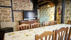A dining area with a table set for four, a television on a wooden cabinet, and a patterned wall.