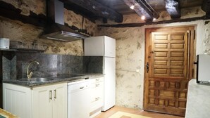 A kitchen with white cabinets, a stainless steel sink, and a wooden door.