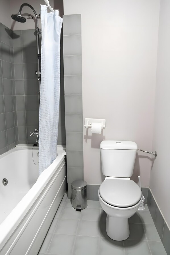 A bathroom with a bathtub, toilet, and shower curtain.