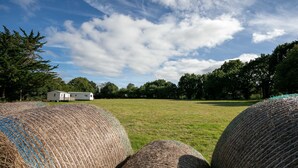 Hay bales in a field with a white trailer in the background. - Mobile Home 'Bikini' with Private Terrace and Private Garden (Plouha)